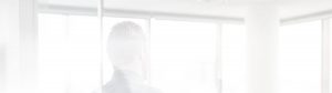 A blurred, light-filtered background showing a person standing near large windows with white frames, possibly in an office setting. The image appears overexposed, depicting a serene, bright ambiance.