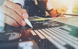 A person uses a pen to interact with charts and graphs overlaid on a desk, depicting financial analysis and lead generation best practices. A rising line graph symbolizes growth, alongside bar charts and numbers. The scene conveys data-driven decision-making in a business context.