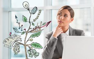 A woman in a gray suit sits at a desk, looking thoughtfully at a drawing of a tree. The tree is adorned with symbols like clocks, graphs, and currency, with "Success" and elements of content marketing written among its branches. A laptop is visible in the foreground.
