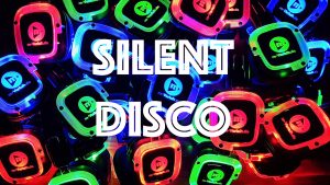 A vibrant display of brightly colored headphones with LED lights in green, red, and blue, surrounding bold white text that reads "SILENT DISCO.
