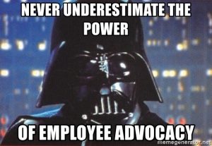 A character in a dark suit and helmet stands with the text: "Never underestimate the power of employee advocacy." The blurred interior background enhances the dramatic effect, reflecting B2B digital marketing trends.