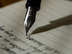 A close-up of a fountain pen writing cursive on lined paper illustrates the art of traditional handwriting. The metal nib is in focus, while the ink forms elegant loops and swirls, much like mastering Title Case vs Sentence Case in written communication.
