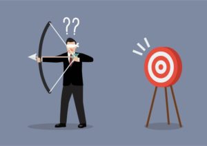 A blindfolded person in a suit is attempting to shoot an arrow with a bow towards a target. The person has question marks above their head, indicating confusion. The target, a classic red and white bullseye, is positioned to the right.