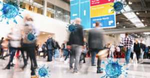 A busy indoor convention center with blurred people walking. Large blue virus icons are overlaid on the image, illustrating the presence of viruses in crowded places. Signs above direct to various sections like VIP Lounge and Press Center.