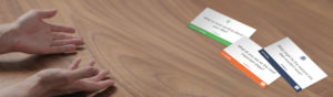A pair of hands on a wooden table next to several cards with text. The cards feature questions about teams and work impact. The focus is on collaboration and team reflection.
