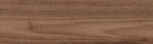 Close-up of a wooden surface with a natural grain pattern. The wood has a warm brown color with visible lines and subtle variations in tone, giving it a textured appearance.