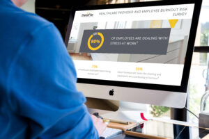 A person viewing a computer screen displaying a survey titled "Healthcare Provider and Employee Burnout Risk Survey." The screen highlights that 90% of employees are dealing with stress at work, with additional statistics at the bottom.