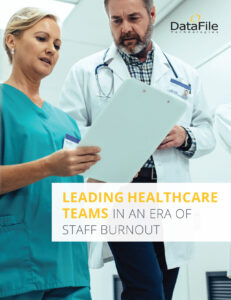 Two healthcare professionals review a document together. A woman in scrubs and a man with a stethoscope stand under bright lights. Text overlay reads, "Leading Healthcare Teams in an Era of Staff Burnout." DataFile Technologies logo is visible.