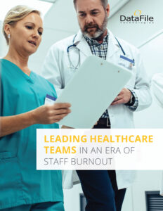 Healthcare professionals reviewing documents in a hospital setting. A woman in scrubs and a man in a lab coat focus on a clipboard. The text reads "Leading Healthcare Teams in an Era of Staff Burnout." Logo: DataFile Technologies.