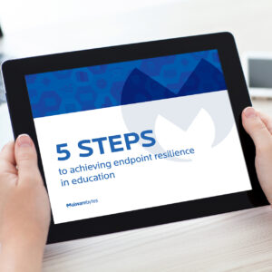 A person holds a tablet displaying a title slide for "5 Steps to Achieving Endpoint Resilience in Education" by Malwarebytes.