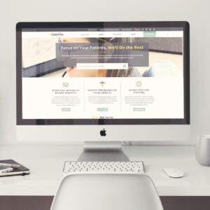 A modern desktop computer displaying a website with the slogan "Focus on Your Patients, We'll Do the Rest." The site offers solutions related to record requests, HIPAA liability, and HIM staffing. The computer is on a clean, minimalist desk.