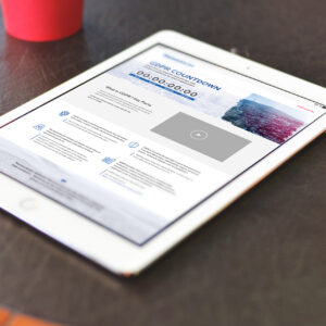 A white tablet on a dark surface displays a webpage titled "GDPR Countdown" with a timer set to zeros. The page contains text sections and a large play button in the center. A red cup is partially visible in the top left corner.