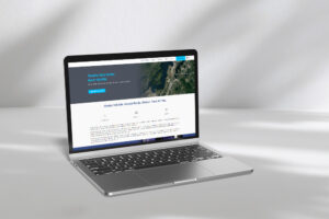 A laptop sits on a white surface, displaying a web page with a header image of a city. The website seems to be about a data center, with options related to disaster recovery and business continuity visible.