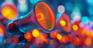 Close-up of a microphone with an orange and red filter, highlighted against a blurred background of circular lights in blue, orange, and red hues. The scene creates a vibrant and energetic atmosphere.