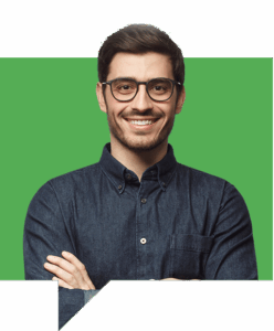 A man with short dark hair, glasses, and a beard smiles with his arms crossed. He is wearing a dark denim button-up shirt and stands in front of a green background with a white border.